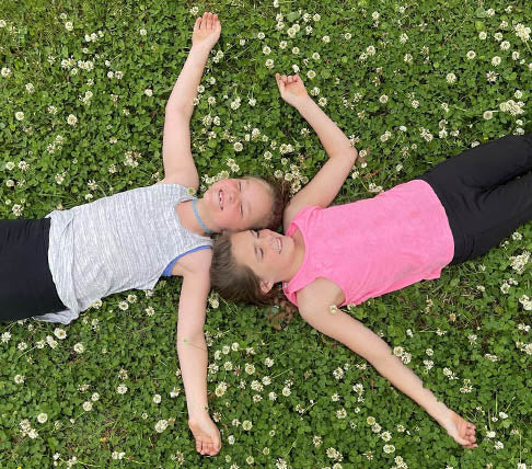 2 children laying in a lawn of clover